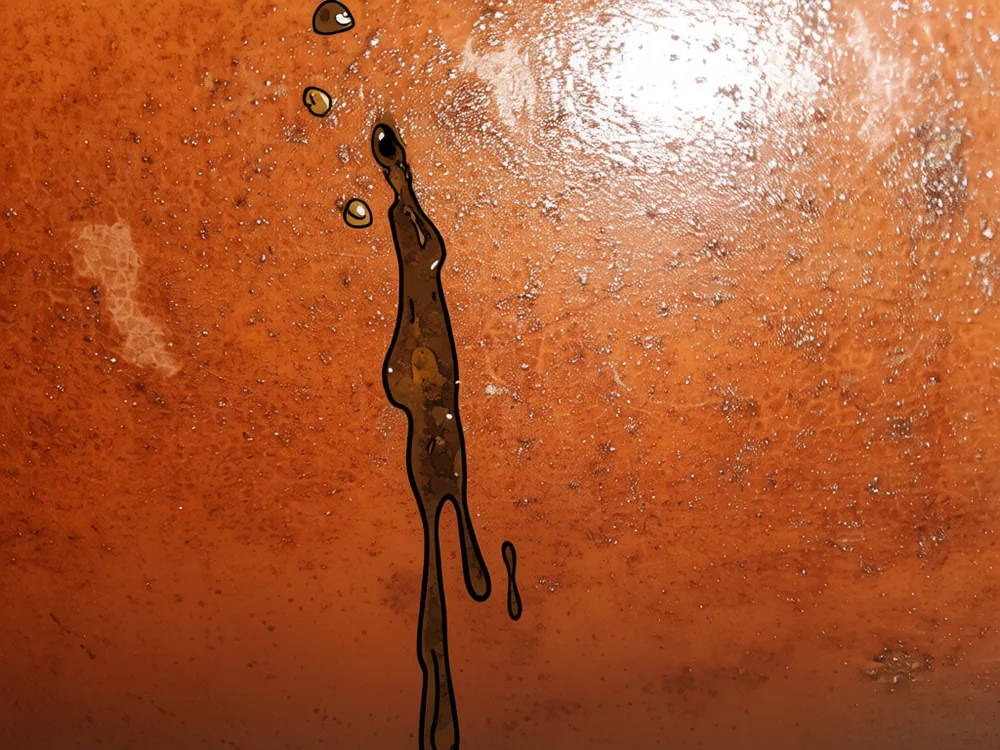 Sludge weeping from a pinhole on the side of a steel oil tank